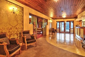 Experience the classic charm of our lobby, featuring a polished floor, high ceiling, and elegant decor.